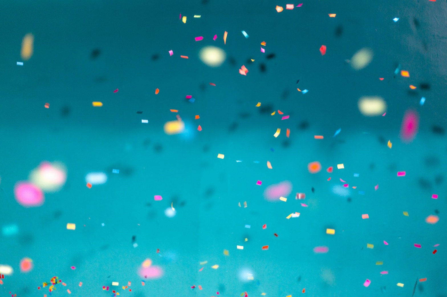 Confetti falling in front of a teal background